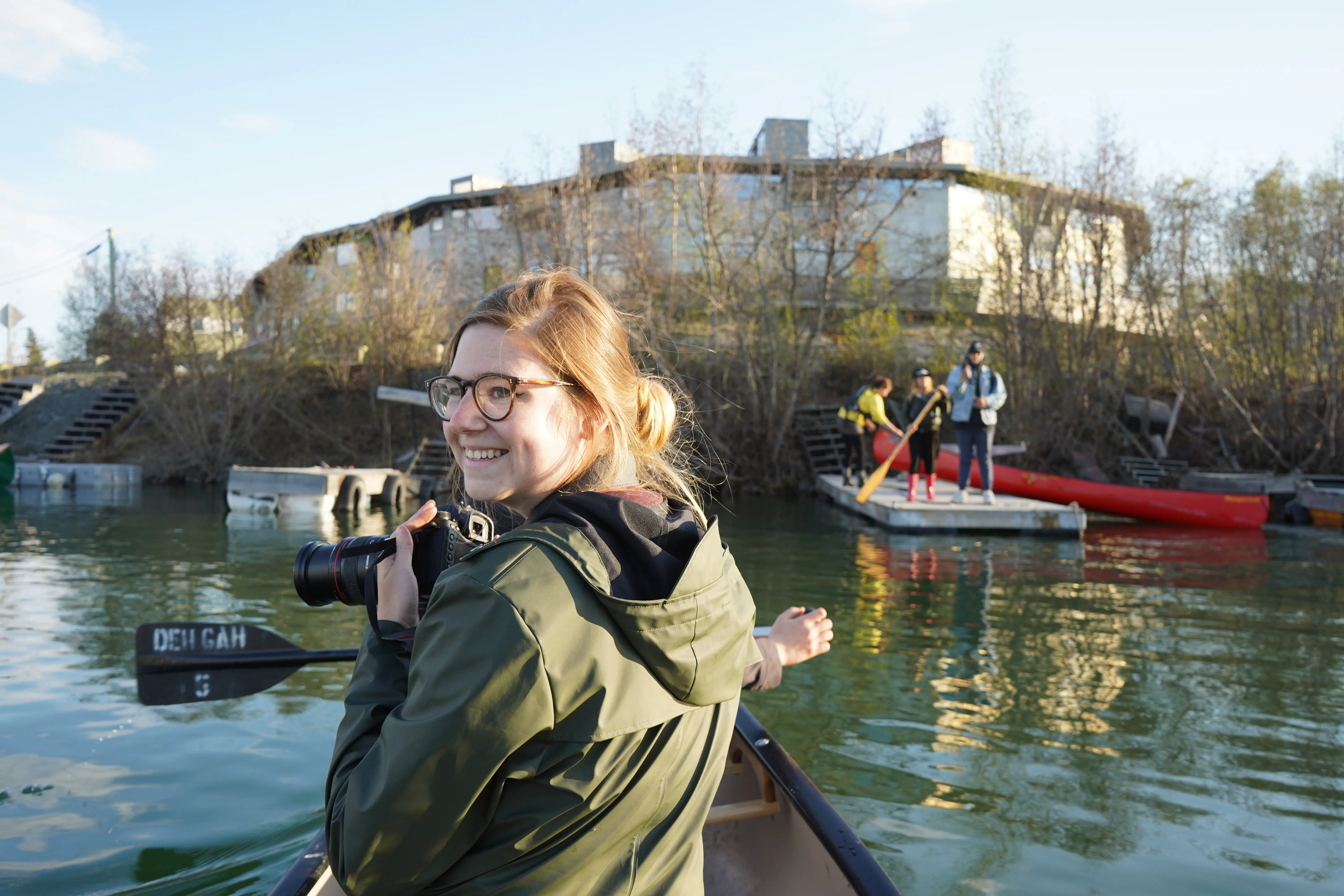 A woman holding a camera in a canoe near Yellowknife.